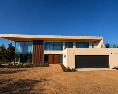 Πρόσοψη σύγχρονης luxury κατοικίας με minimal design, μεγάλες υαλώσεις και ενεργειακά κουφώματα αλουμινίου.
